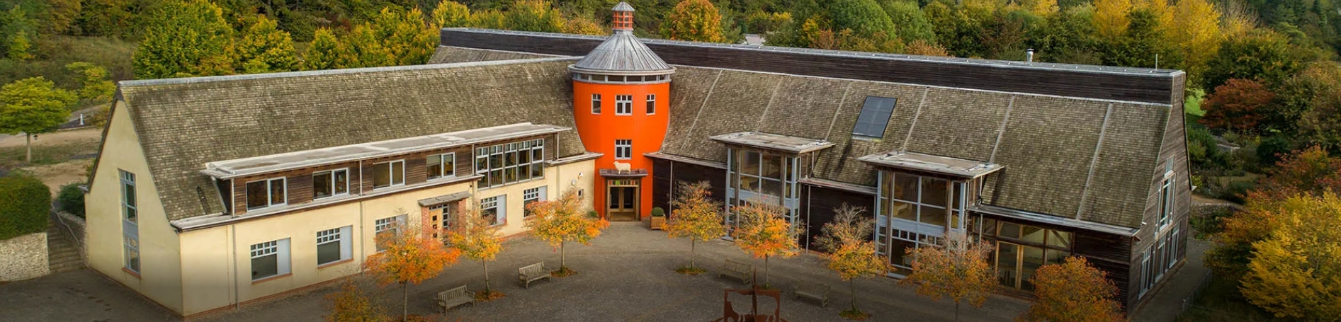 Sheepdrove full width A building with orange turret, with trees in front of it