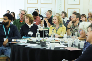 A picture of a diverse group of people watching a workshop.