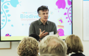 A picture of John Wedgwood Clarke presenting to a group at the RENEW X BookTrust, Biodiversity Storytelling Summit 2023.