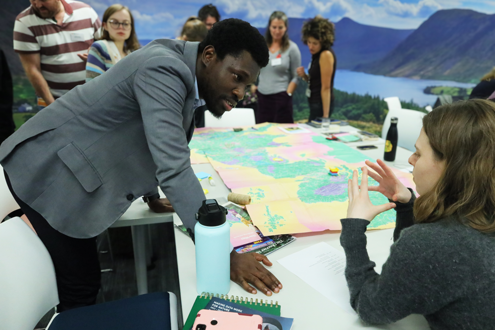 An image of PhD candidate Patrick Oku Quaye discussing research at the Biodiversity Parliament 2023.